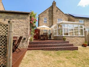 a stone house with a patio with a table and chairs at Col du Crich in Matlock