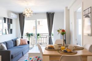 sala de estar con mesa y sofá azul en Playa El Palo Apartment by SharingCo, en Málaga