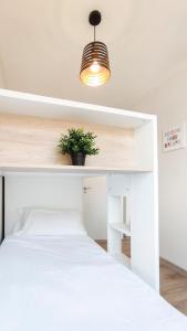 1 dormitorio con cama blanca y maceta en Playa El Palo Apartment by SharingCo, en Málaga