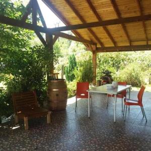 eine Terrasse mit einem Tisch, Stühlen und einem Fass in der Unterkunft Cabañas los Pinos in Villarrica