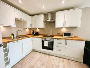 a kitchen with white cabinets and a sink and a microwave at Seaview Central Brighton One Bedroom Flat in Brighton & Hove