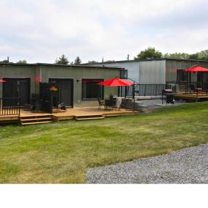 a building with a deck with tables and red umbrellas at Cribs on the Hill in Picton