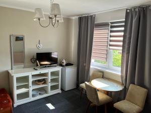 a living room with a television and a table and chairs at Pokoje gościnne in Dźwirzyno