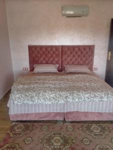 een slaapkamer met een groot bed met een roze hoofdeinde bij Villa khaddouj Marrakech in Marrakesh