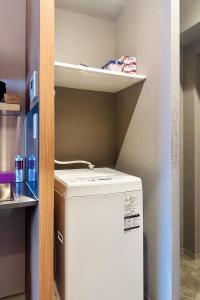 a small kitchen with a refrigerator and a shelf at Apartment Hotel 11 Namba Minami Shin-Imamiya in Osaka