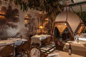 a restaurant with tables and chairs and a wall mural at Hotel Casa Palacio María Luisa in Jerez de la Frontera