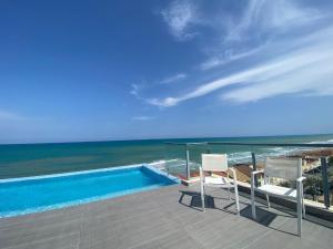 a balcony with a pool and two chairs and the ocean at PISO-DEL-PLAYA in Guardamar del Segura