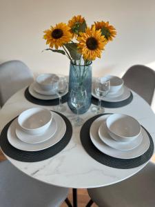 a table with plates and glasses and a vase with flowers at Cambridge Apartment with free onsite parking in Cambridge
