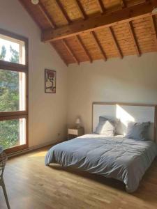 ein Schlafzimmer mit einem Bett und einem großen Fenster in der Unterkunft Superbe Maison d’Architecte au cœur du Vercors in Autrans
