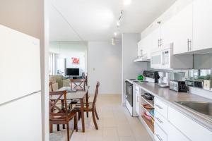 a kitchen with white cabinets and a table with chairs at Light & Airy Waikiki Condo with Private Lanai condo in Honolulu