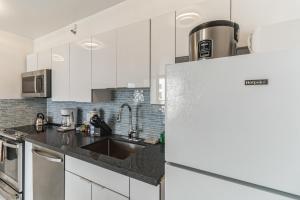 a kitchen with white cabinets and a refrigerator at Standard Ocean View Condo - 36th Floor, Free parking & Wifi condo in Honolulu