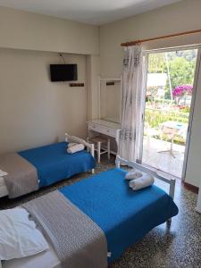 two beds in a room with a window and a desk at Rois Appartments in Poros