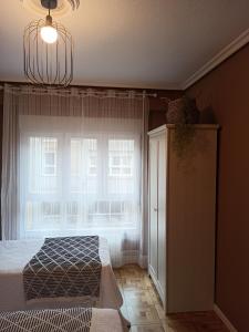 a bedroom with a bed and a window and a chandelier at Piso céntrico Calma Costera in Santander