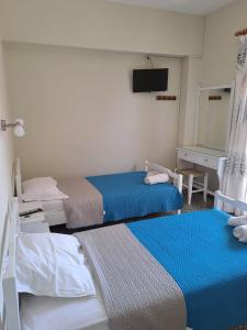 a hotel room with two beds and a television at Rois Appartments in Poros