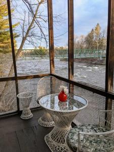 una mesa y sillas en un porche con vistas al río en Le Perché-sur-la-rivière, en Joliette