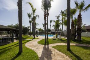a path through a resort with palm trees and a pool at Oasi lamia - 3 in Mazara del Vallo +30 photos
