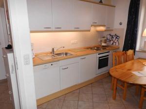 a kitchen with white cabinets and a wooden table at Oland-3 in Brösum