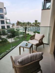 Address Beach Resort Fujairah - 2 bedroom apartment في الفجيرة: شرفة مع طاولة وكراسي وإطلالة على المحيط