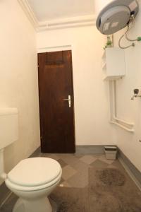 a bathroom with a toilet and a brown door at Maple place in Velika Gorica