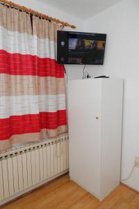 un televisor en la parte superior de un armario blanco frente a una cortina en Maple place, en Velika Gorica