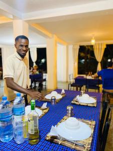 a man is standing in front of a table at Fig Tree Lodge Camp in Mto wa Mbu