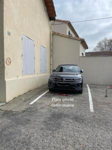 une voiture garée dans un parking à côté d'un bâtiment dans l'établissement Au calme dans le centre avec terrasse et clim, à Saint-Rémy-de-Provence