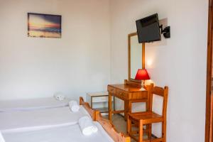 Pokój z 2 łóżkami, biurkiem i telewizorem w obiekcie Katerina Studios & Apartments w Sidari