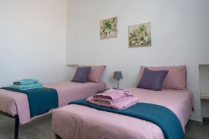 two beds in a room with pink and purple at Residence Pace & Relax in Marina di Grosseto