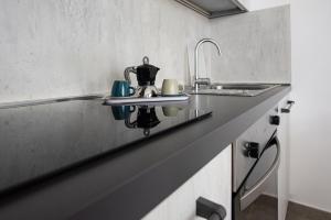 un bancone della cucina con lavandino e bollitore per il tè di Residence Pace & Relax a Marina di Grosseto