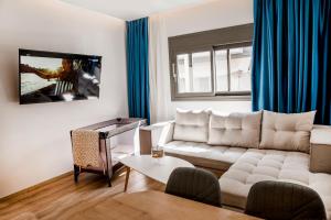 a living room with a white couch and a tv at Magdalena Suite 3.0 in Heraklio