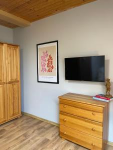 a room with a dresser and a flat screen tv on a wall at VillaAnita in Augustów