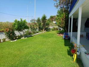 a yard next to a house with a green lawn at ALMADOL HOUSE Chalkidiki Τρυπητή Χαλκιδικής in Nea Roda