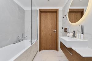 La salle de bains est pourvue de 2 lavabos et d'une porte en bois. dans l'établissement GWARNA Aparthotel City Center Wrocław by Renters, à Wrocław