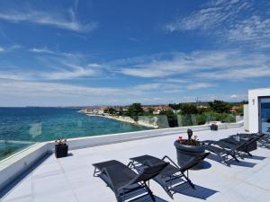 a patio with chairs and the ocean in the background at Apartments Dalmatia Infinity in Bibinje