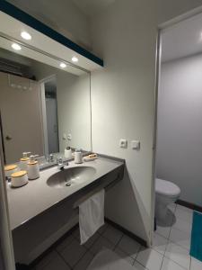 a bathroom with a sink and a mirror and a toilet at Un petit joyau in Le Diamant