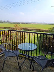 a table and chairs on a deck with a view of a field at Barley View in Aylmerton