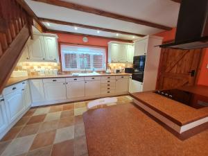 uma grande cozinha com armários brancos e uma janela em Barley View em Aylmerton