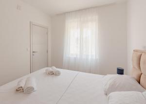 a white bedroom with towels on a bed at White Apartment in Kumbor