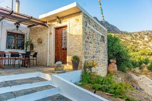 una casa in pietra con una porta in legno e un tavolo di MaciliaVilla. a Ierápetra