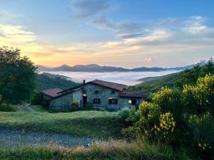 una vecchia casa in pietra su una collina con una montagna nebbiosa di Agriturismo Giandriale a Tavarone