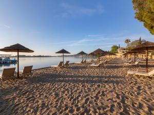 a sandy beach with chairs and umbrellas on it at Dreams Corfu Resort & Spa - All Inclusive in Gouvia