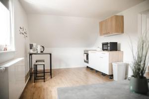 uma pequena cozinha branca com um balcão e uma mesa em Modernes Apartment Schwarzenfeld em Schwarzenfeld