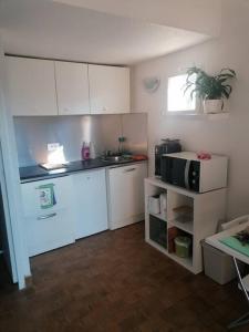 a small kitchen with white cabinets and a sink at Proche de la plage les hauts du port in Saint-Cyr-sur-Mer +13 photos