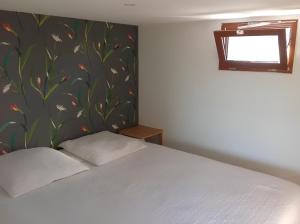 um quarto com uma cama branca e papel de parede floral em L'escale Kerhorre em Le Relecq-Kerhuon