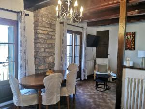 a dining room with a wooden table and white chairs at Gîte Le Barry in Le Caylar