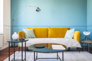 een woonkamer met een gele bank en 2 tafels bij Blue Velvet Reims in Reims