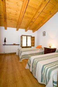 3 łóżka w pokoju z drewnianym sufitem i drewnianą podłogą w obiekcie El Molino de la Hiedra w mieście Albeta