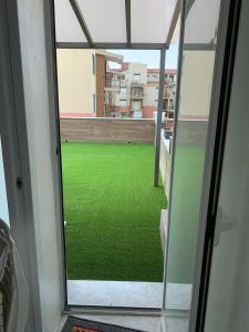 a view of a green yard from a glass door at Le rocce nere in Giardini Naxos