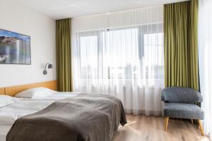 ein Schlafzimmer mit einem Bett, einem Stuhl und einem Fenster in der Unterkunft Hotel Selfoss in Selfoss