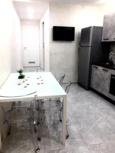 a kitchen with a white table and a refrigerator at Le rocce nere in Giardini Naxos